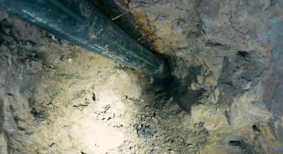 Plumber inserting a pipe underground to repair a burst water line